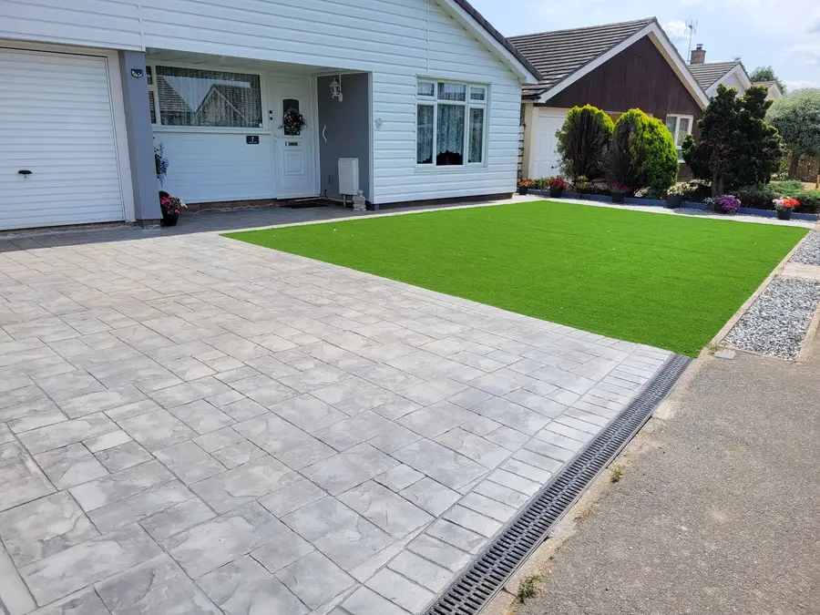 Grey pattern imprinted concrete driveway with artificial lawn